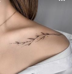 the back of a woman's shoulder with small tattoos on her left shoulder and an arrow