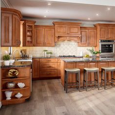 a large kitchen with wooden cabinets and counter tops is pictured in this image, there are stools at the center of the island