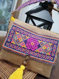 a small purse sitting on top of a wooden table next to a lantern and some tassels