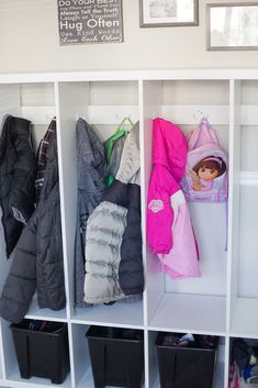 the coat rack is filled with coats and other items in black bins on white shelves