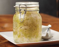 a glass jar filled with food sitting on top of a white plate next to a spoon