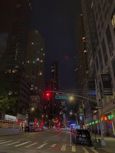 a city street at night with traffic lights and tall buildings