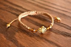 Handmade bracelet with cross, adjustable. Gold cross, brown and gold beads, beige satin cord. Adjustable Gold Beaded Cross Bracelets, Adjustable Brown Cross Bracelet, Bracelet With Cross, Woven Bracelet, Macrame Bracelets, Gold Cross, Handmade Bracelet, Friendship Bracelet, Gold Beads