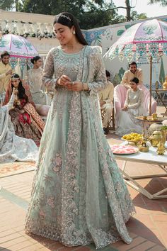 a woman in a blue and pink lehenga standing on steps with her hand on her hip