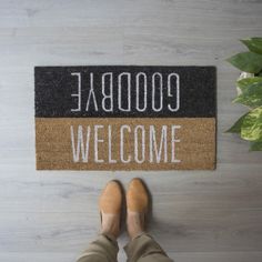 a person standing in front of a welcome mat with the words goodbye written on it