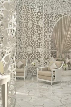 a living room with white furniture and walls covered in intricate paper art work on the walls