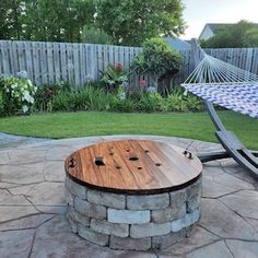 a hammock in the middle of a yard with a wooden table and bench