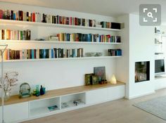 a living room filled with lots of books on top of white shelving unit units