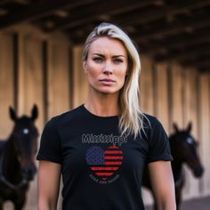 a woman standing in front of horses wearing a t - shirt with the word mississippi on it