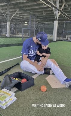 a baseball player sitting on the ground with his son