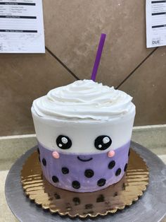 there is a cake that looks like a cupcake with a face on it and a purple straw sticking out of the top