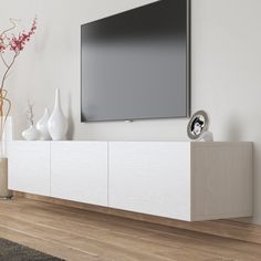 a flat screen tv sitting on top of a white entertainment center next to vases