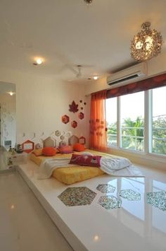 a living room filled with lots of furniture next to a large window covered in orange curtains