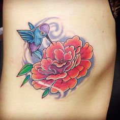 a woman's stomach with a flower and bird tattoo on it