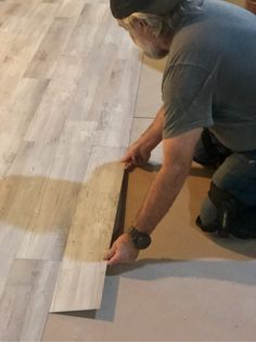 a man laying wood on top of a hard wood floor