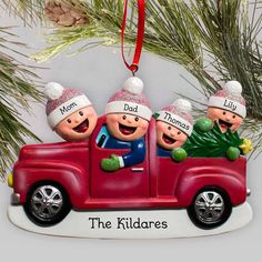 three people riding in the back of a red truck ornament on a christmas tree