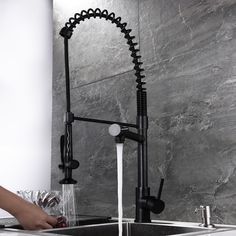 a person washing their hands under a faucet in a kitchen sink next to a marble wall