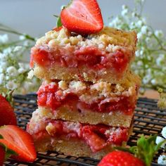 three slices of strawberry crumb bars stacked on top of each other with strawberries