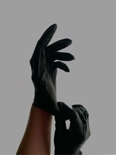 a person wearing black gloves and holding their hands up in the air