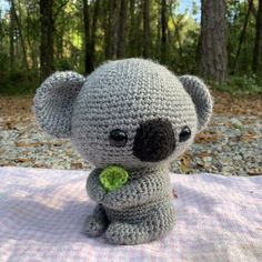 a small crocheted koala bear sitting on top of a blanket