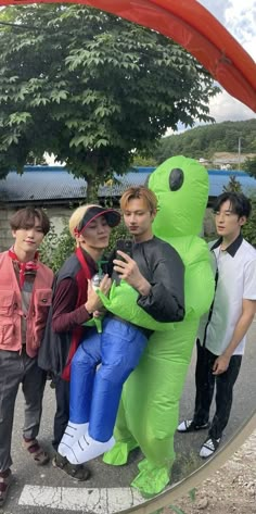 some people are posing for a photo in front of a giant green teddy bear costume