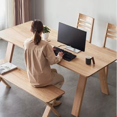 a woman sitting at a desk with a computer on her lap and keyboard in front of her