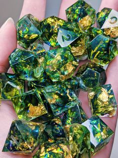 green and gold foiled glass cubes are being held in the palm of someone's hand