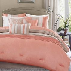 a bed with pink comforter and pillows in a room