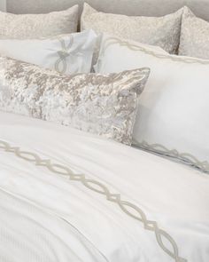 a bed with white sheets and pillows on top of it