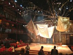 an empty stage with people sitting on the seats and drapes hanging from the ceiling