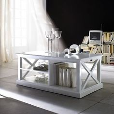 a white coffee table sitting in front of a book shelf filled with books and wine glasses