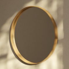 a round mirror hanging on the side of a wall next to a shadow cast wall