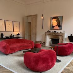 a living room filled with red couches and chairs in front of a fire place