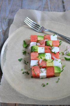 a white plate topped with slices of watermelon and cucumber next to a fork