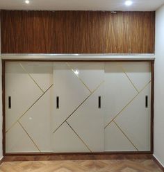 an empty room with some white and gold doors on the wall next to wood flooring