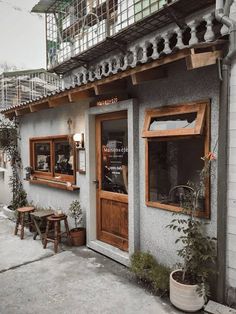 the outside of a restaurant with wooden doors and windows, potted plants on the sidewalk