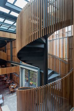 a spiral staircase in the middle of a restaurant with wooden walls and floor to ceiling windows