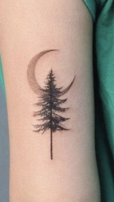 a pine tree with a crescent tattoo on the arm