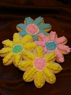 cookies decorated with icing and flowers on a brown surface, ready to be eaten