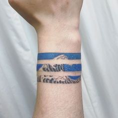 a man's arm with a wristband that has mountains and waves on it