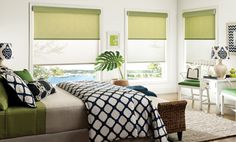 a bed room with a neatly made bed and green shades on the window sill