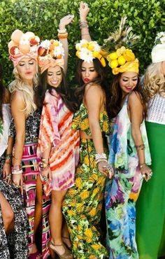 a group of women standing next to each other in dresses and headbands with flowers on their heads