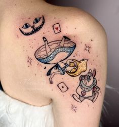 a woman's shoulder with tattoos on it and an image of a cat, dog, and fish