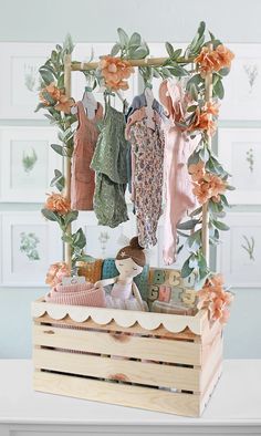 a wooden box with clothes hanging from it's sides and flowers on the top