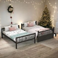 two twin beds in a room with christmas lights on the wall and a tree behind them