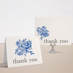 two thank you cards with blue flowers on them sitting next to a silver candle holder