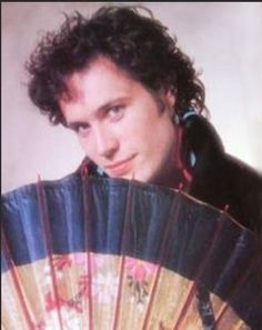 a man with curly hair is holding an accordion