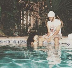 a man kneeling down next to a woman in a pool