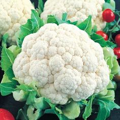 several cauliflower heads with green leaves and red berries