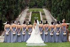 a bride and her bridal party standing in front of an ornamental garden with fountain